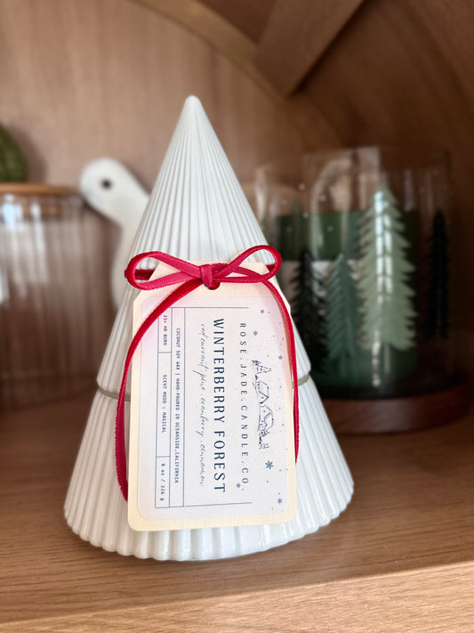 Decorative candle shaped like a Christmas tree with a label on a wooden surface